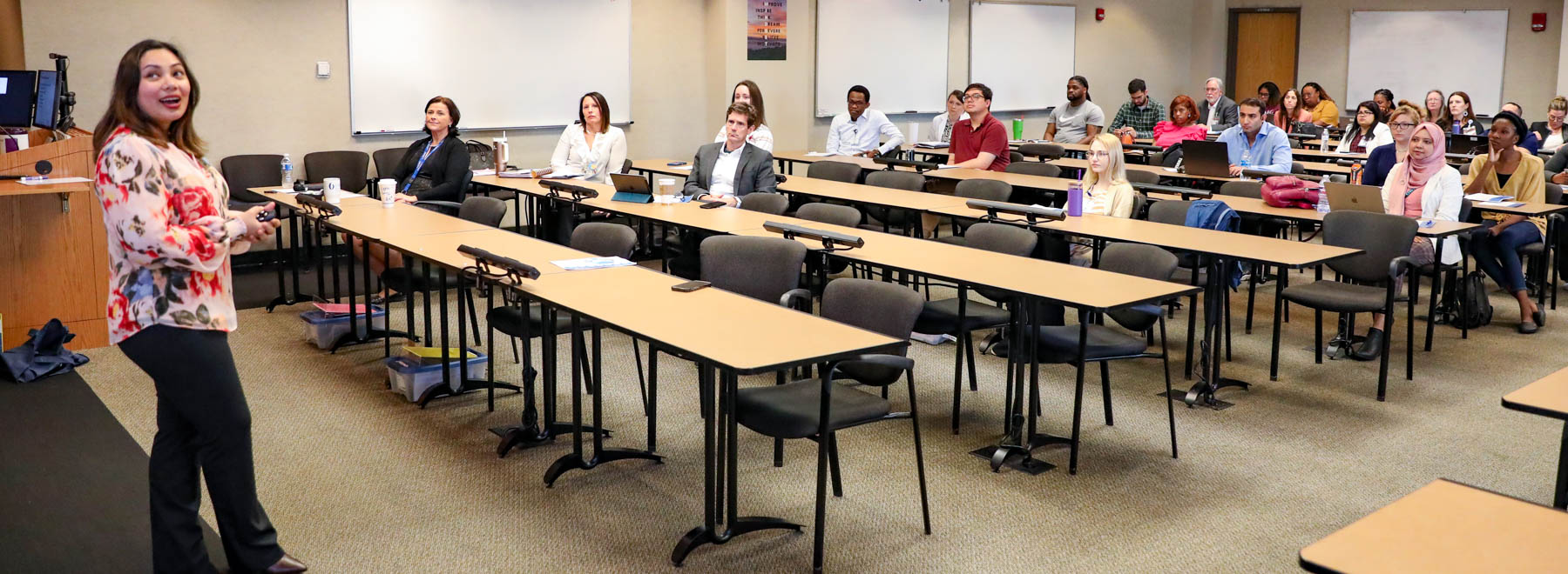 Student presenting her research to a crowded room